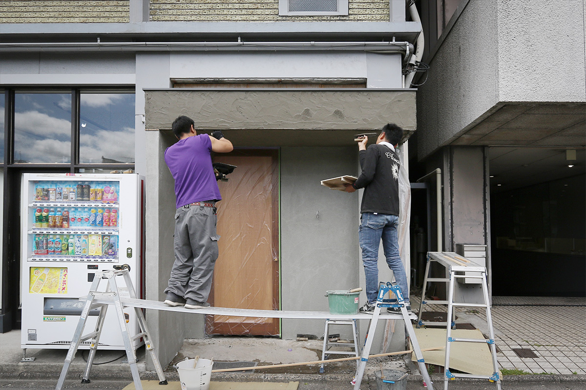 京都ビルの外壁、エントランスの壁に職人がモルタルを塗っています